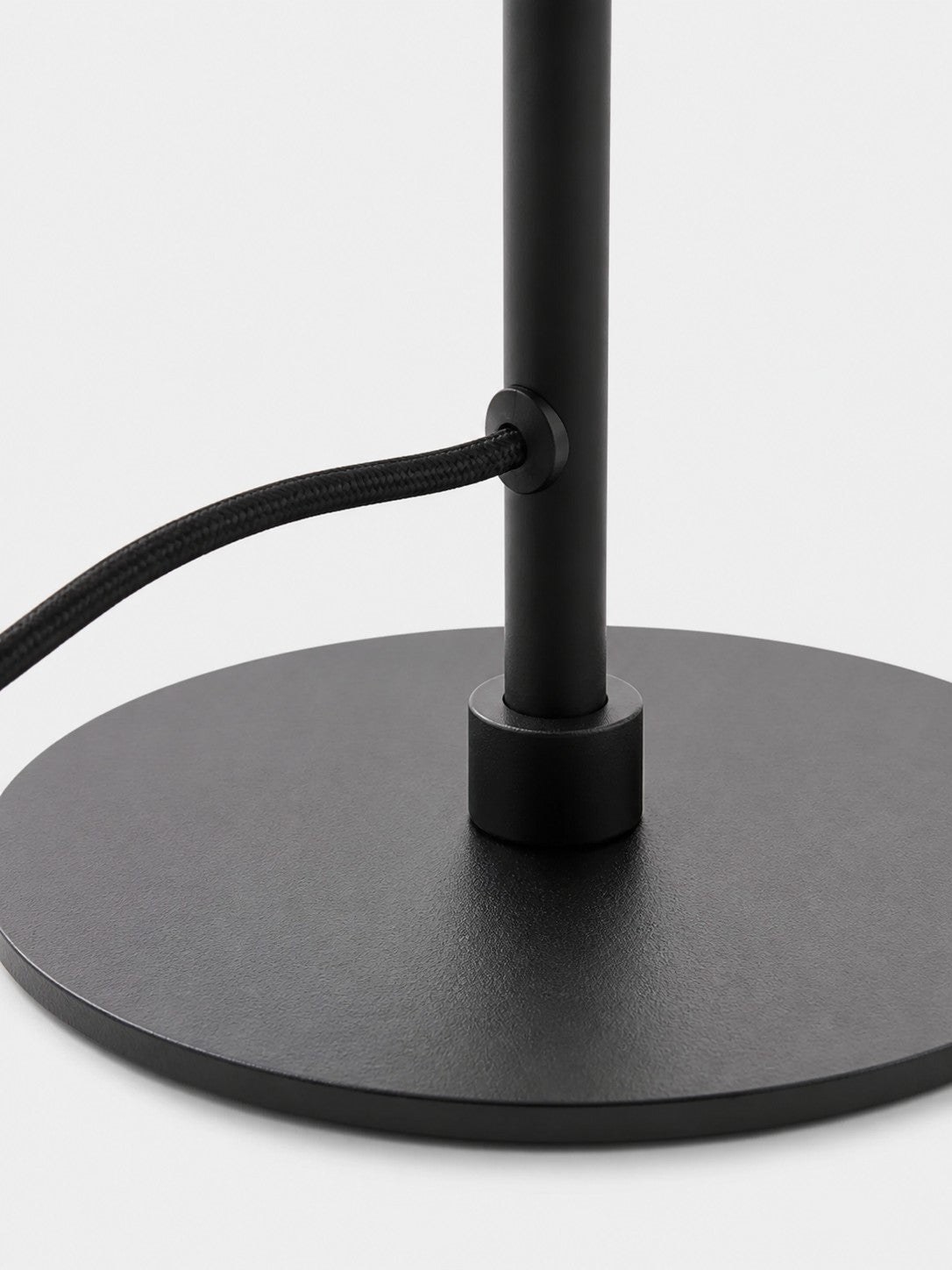 Detailopname van de matzwarte basis en de stoffen kabel.