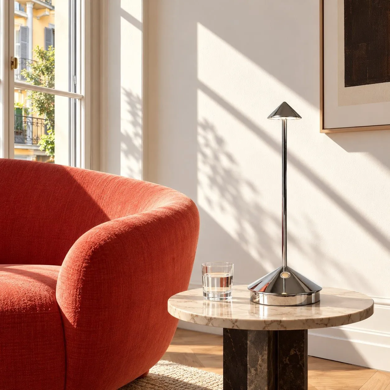 Lampe de table LED rechargeable chrome près d'un fauteuil lounge rouge